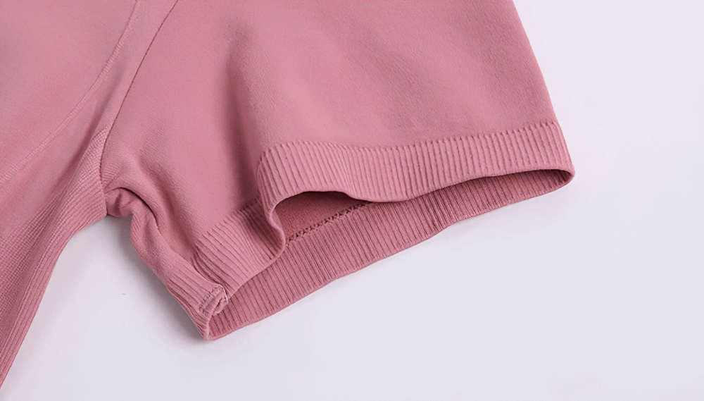 Close-up of a pink short-sleeve breathable fitness t-shirt for women, showing ribbed hem detail, perfect for running and gym sessions.